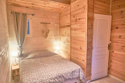 - une chambre avec un lit dans un mur en bois dans l'établissement Cabane au milieu des pins - Domaine Temali, à Labouheyre