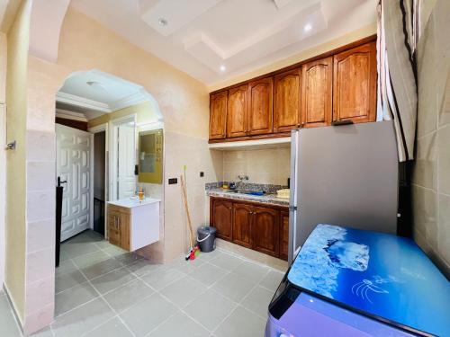 uma cozinha com armários de madeira e um frigorífico em Famille Hanae appartement avec terasse em Marrakech