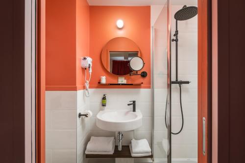 an orange bathroom with a sink and a mirror at Hotel Archetype Etoile in Paris