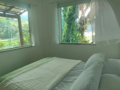 a bed in a white room with a window at Pousada Onda de Mar in Angra dos Reis