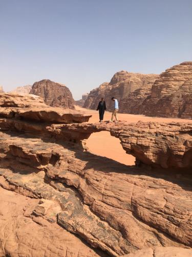 2 personnes marchant sur un pont rocheux dans le désert dans l'établissement Bedouin experiences, à Aqaba