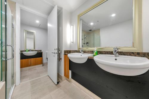 a bathroom with two sinks and a large mirror at Fabulous Corner Apartment w/ Dazzling Harbour View in Auckland