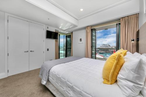 1 dormitorio con cama blanca y ventana grande en Fabulous Corner Apartment w/ Dazzling Harbour View, en Auckland