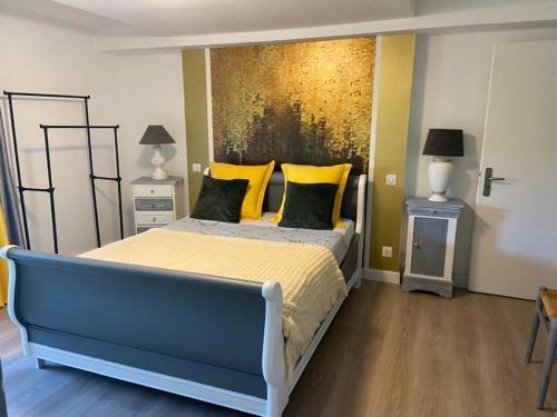 ein Schlafzimmer mit einem blauen Bett und gelben Kissen in der Unterkunft Le volcan in Rochefort