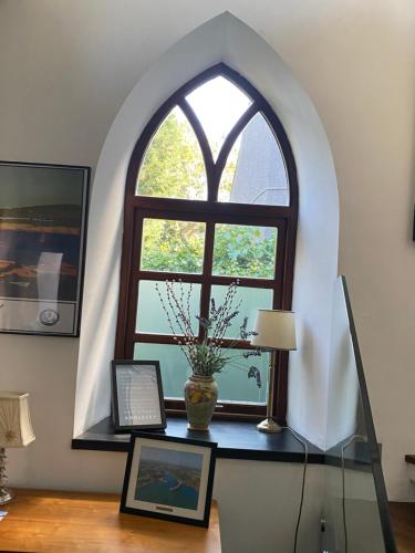 an arched window in a room with a table with a vase at Converted chapel - Sant Pedr Newydd - with sea views in Amlwch