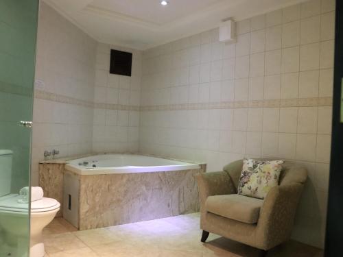y baño con bañera, silla y aseo. en Guarita Park Hotel - By Life Hotéis, en Torres