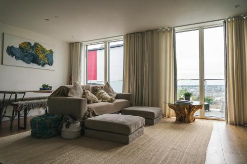 uma sala de estar com um sofá, uma mesa e janelas em Penthouse at the Chocolate Box em Bournemouth