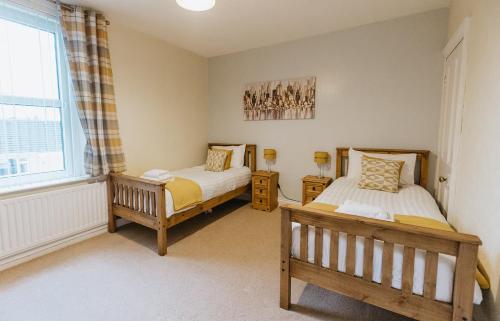 a bedroom with two beds and a window at Winnie's Cottage - 3 Bed Accommodation in Cumbria in Mealsgate