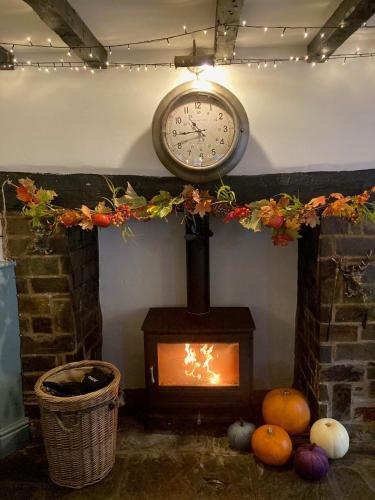 a fireplace with a clock on the wall and a fire at Blue Ball Inn, Sandygate, Exeter in Exeter