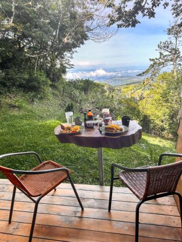 a table with food sitting on a deck with two chairs at Casa Por Fin in Monteverde Costa Rica
