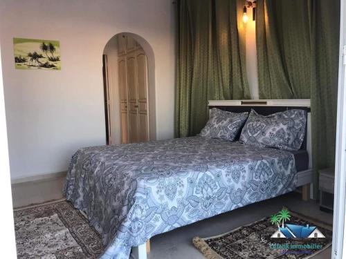 a bedroom with a bed with a gray comforter at Villa Amine Flouka in Houmt Souk