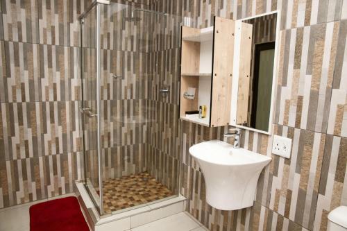 a bathroom with a shower and a sink and a mirror at Boeketlong Lodge in Jane Furse
