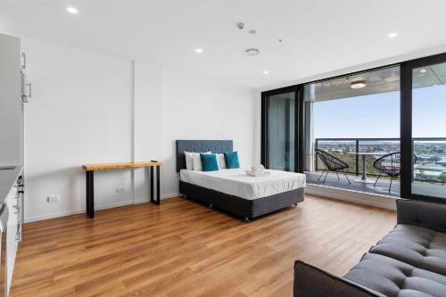 a bedroom with a bed and a couch and a large window at Manukau Studio Apartments in Auckland