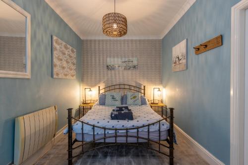 1 dormitorio con cama de metal y paredes azules en Beach House, en Lytham St Annes
