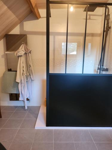 a glass shower door in a room with a tiled floor at ELLA in Aragnouet