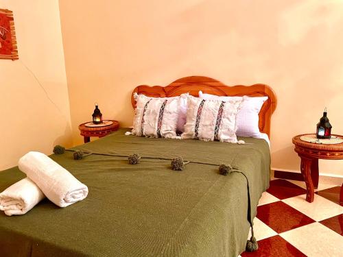 a bedroom with a bed with a green blanket and pillows at Belle villa privé in Ounara