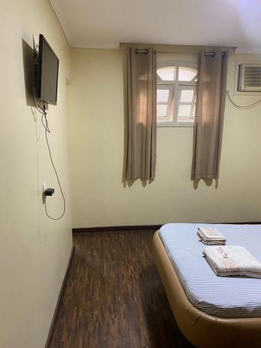 Una pequeña habitación con una cama y un televisor. en Hotel Lido (Adult Only), en Río de Janeiro