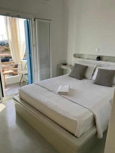 a large white bed in a bedroom with a balcony at Alexandra’s studios in Iraklia