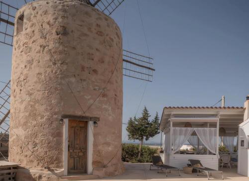 un edificio con una gran torre de piedra junto a una casa en Molino Sa Miranda - Formentera Break, en Sant Francesc Xavier