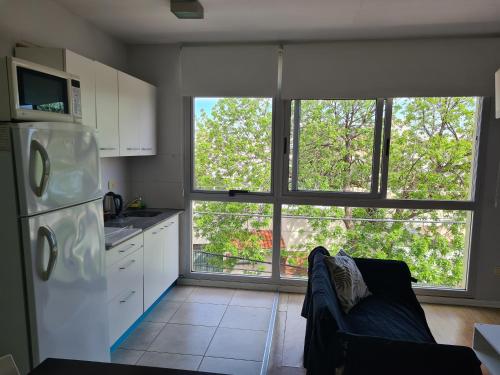 cocina con nevera blanca y 2 ventanas grandes en Departamento luminoso en Bahía Blanca