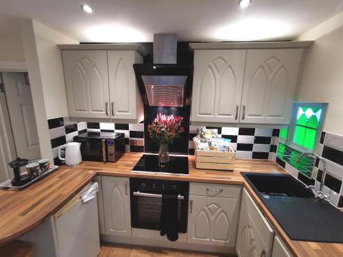a kitchen with white cabinets and a vase of flowers at Castle Annexe from 3 nights in Torquay