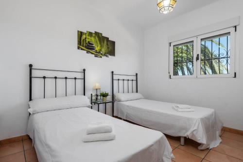 two beds in a room with white walls and windows at Villa Rodrigo - PlusHolidays in Benissa