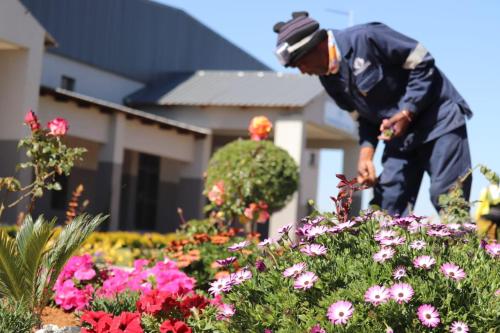 a gardener in front of a house looking at flowers at Boeketlong Lodge in Jane Furse
