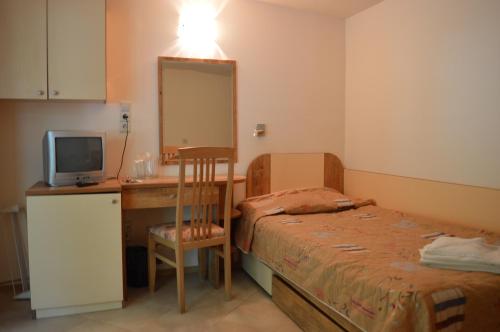a small room with a bed and a desk with a mirror at Villas Holidays in Primorsko