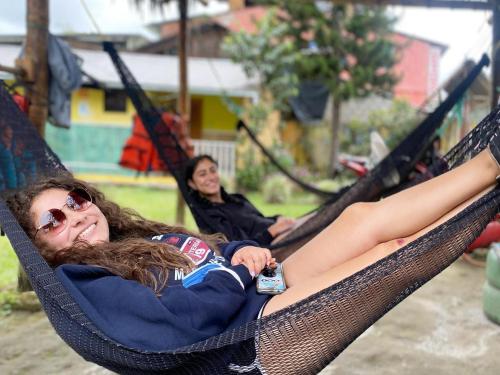 una mujer tendida en una hamaca con una botella de refresco en Hostal Henrry's, en Mindo