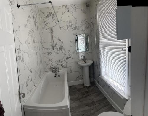 a bathroom with a bath tub and a sink at Excellent 3bed flat in Kent