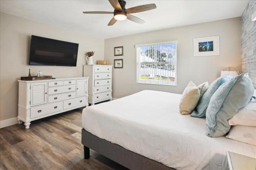 a bedroom with a white bed and a flat screen tv at Royal Blue Dreams flexible rental near Anna Maria Island in Bradenton