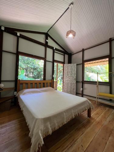 a bedroom with a large bed in a room with windows at OLITAS - Praia de algodões in Marau
