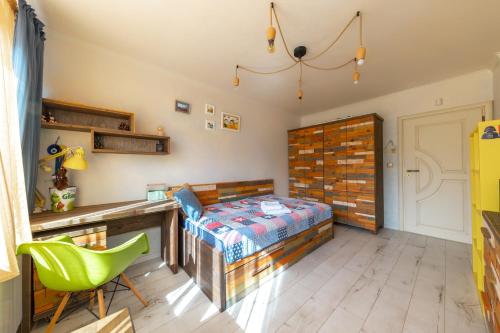 a bedroom with a bed and a desk and a green chair at Happy Town Apartments in Veliko Tŭrnovo