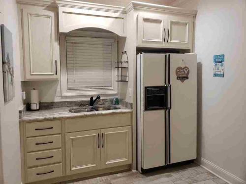  La cuisine est équipée de placards blancs et d'un réfrigérateur. dans l'établissement The Lounge, 