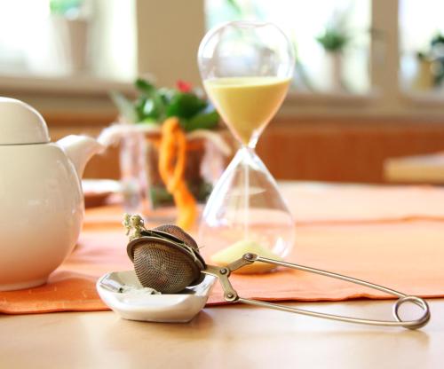 a table with a sand timer and a glass of wine at Gästehaus Lokalaugenschein in Podersdorf am See