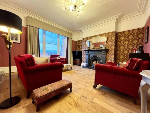 a living room with two red chairs and a fireplace at No. 20 The Headland in Hartlepool