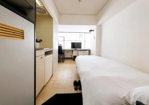 a bedroom with a white bed and a kitchen at ＰＩＡＺＺＡーＵ - Vacation STAY 78015v in Tokyo