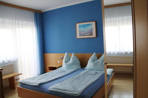 Un dormitorio con una pared azul y una cama con almohadas en Gästehaus Lokalaugenschein, en Podersdorf am See