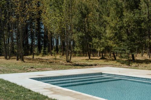 una piscina en un campo con árboles en el fondo en Cabaña de Duendes en San Rafael