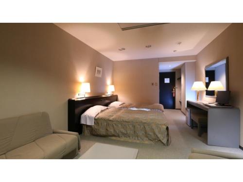 Hotel Silk in Madarao - Vacation STAY 79652v في Iiyama: غرفة نوم بسرير واريكة ومكتب