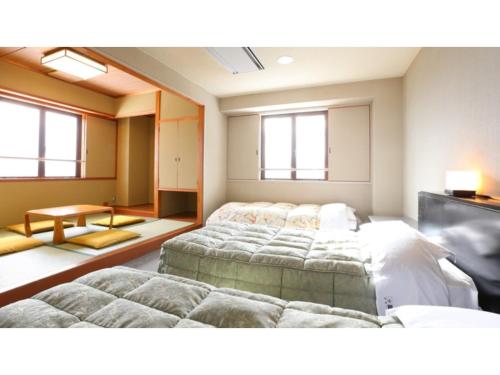a bedroom with three beds and a tv in it at Hotel Silk in Madarao - Vacation STAY 77724v in Iiyama