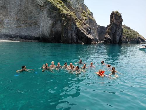 a group of people swimming in the water near a cliff at "Appartamento del Mare Gliaca" con vista Isole Eolie,ampia terrazza,wifi e parcheggio gratuito in Piraino