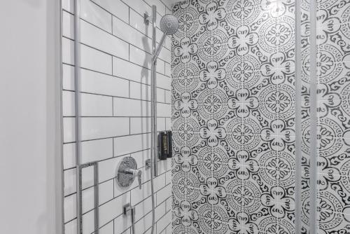a shower in a bathroom with a white tile wall at Cannery Lofts Niagara in Niagara Falls