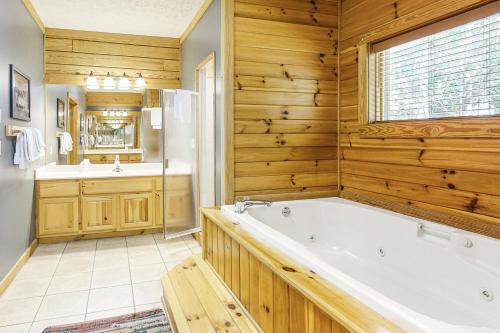 ein Badezimmer mit einer Badewanne, einem Waschbecken und einem Spiegel in der Unterkunft Woodland Hideaway in Gatlinburg