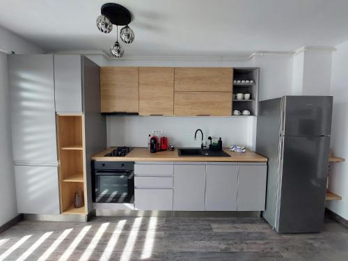 a kitchen with white cabinets and a stainless steel refrigerator at Raluca cozy apartment's in Ploieşti