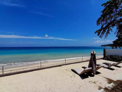Swissfinity Beach Resort في Pangubatan: شاطئ فيه كرسيين ومظله والمحيط