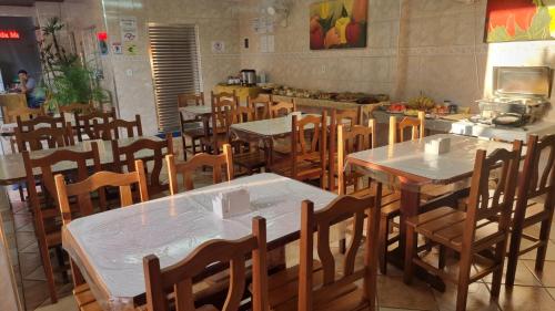 a dining room with tables and chairs and a kitchen at Hotel Pousada Recanto da Madá in Aparecida