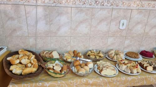 a table with many different types of breads and pastries at Hotel Pousada Recanto da Madá in Aparecida