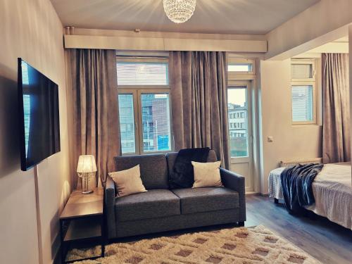 a living room with a couch and a bed and windows at Rovaniemi Cityhome Sunnarborg in Rovaniemi