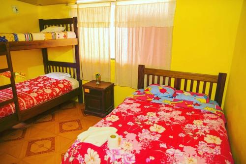 a bedroom with two bunk beds and a red comforter at Hostal Henrry's in Mindo